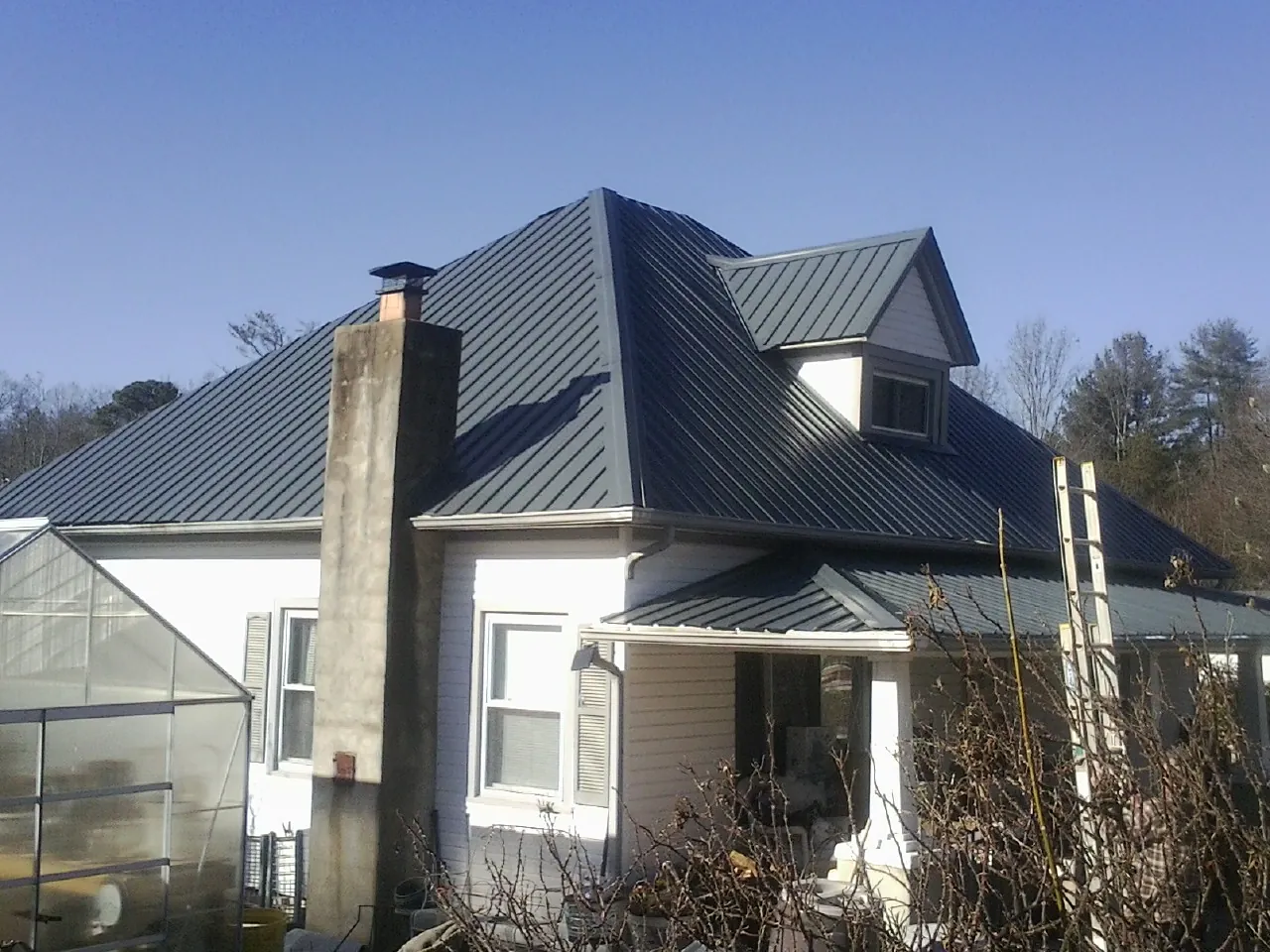 Dark blue standing seam metal roof on a white farmhouse with dormer — Slate & Tile Roof Repair by Roofing Brothers in Lecompton