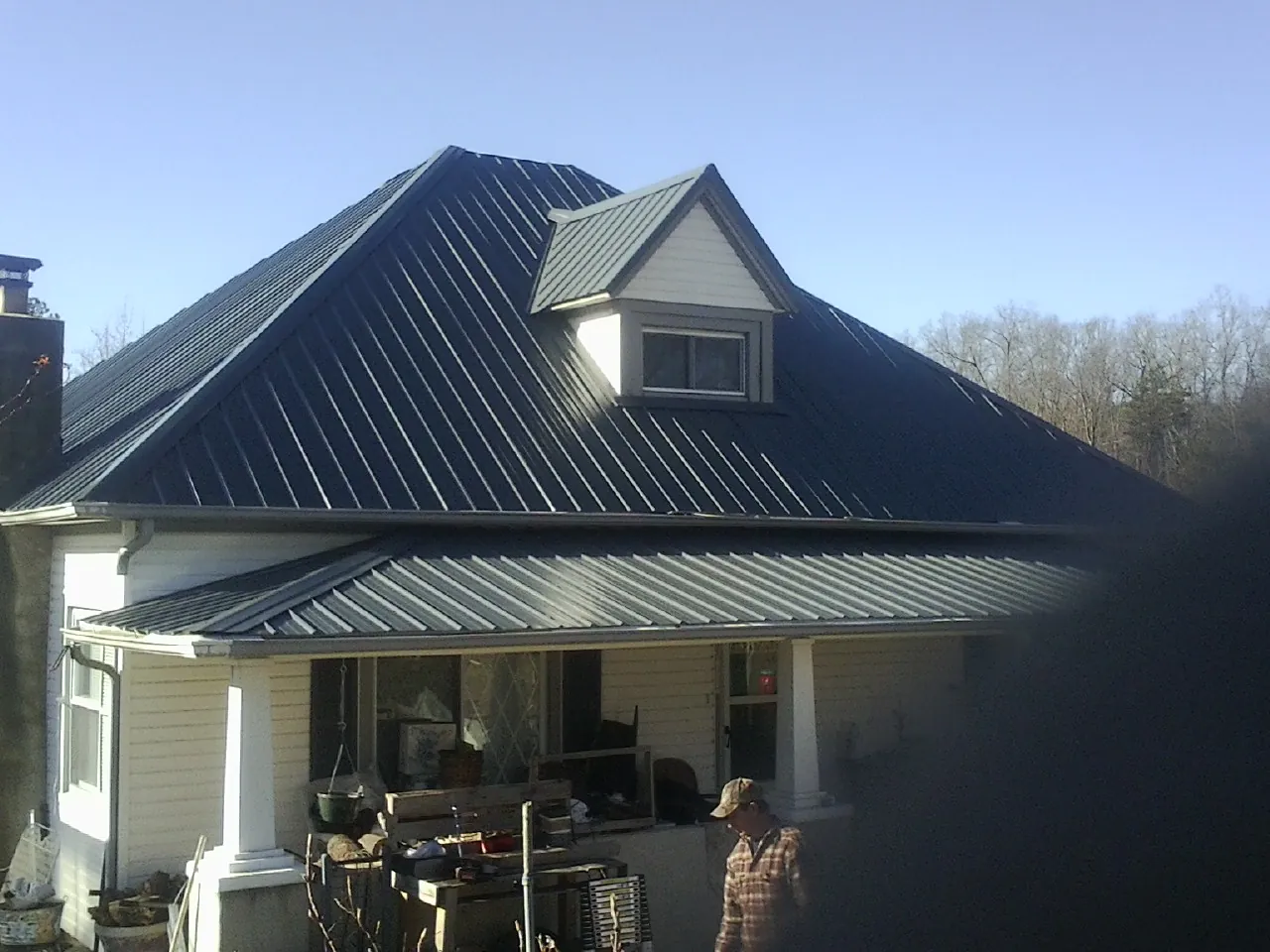 Dark blue standing seam metal roof with a dormer above a front porch in Lecompton