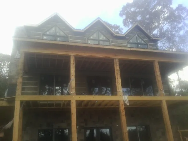 Dormers and porch framing on a large log home under construction — Roof Coating work by our crew in Lecompton