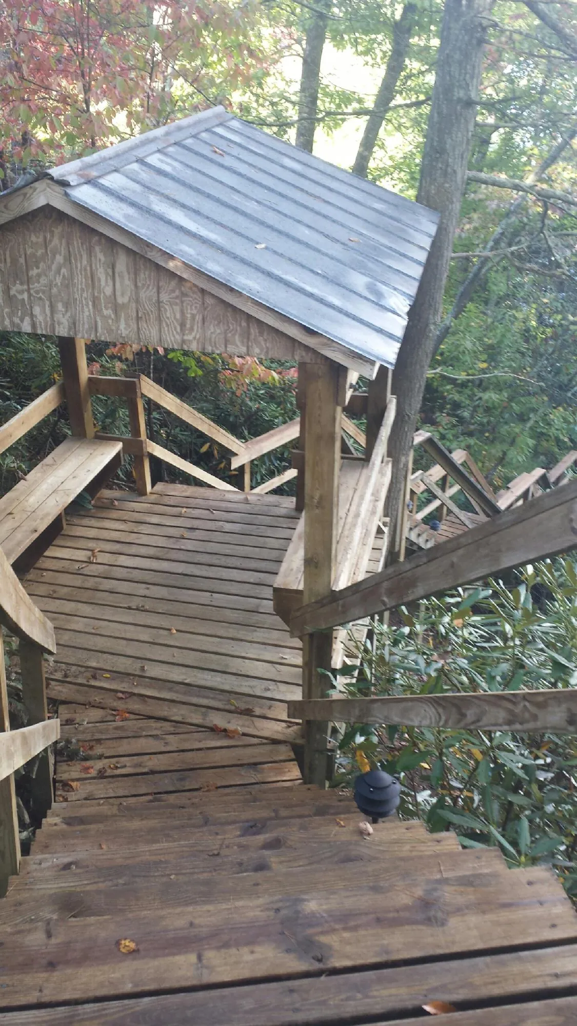 Metal roofed shelter over wooden steps on a wooded walkway — Skylight Repair & Installation work by our crew in Lecompton